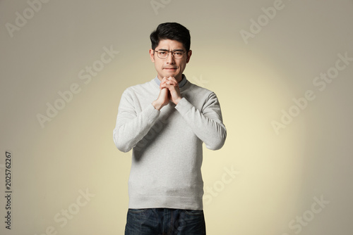 Canvas Print Worried Young Man Clasping Hands in Studio