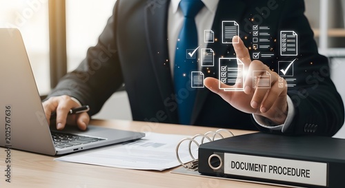 Business professional reviewing digital documents and procedures with laptop and binder