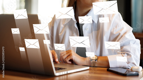Fotografi Sending and receiving emails while working on a laptop in a busy office setting