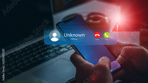 Foto Scam call warning on smartphone during evening work hours at home office setup