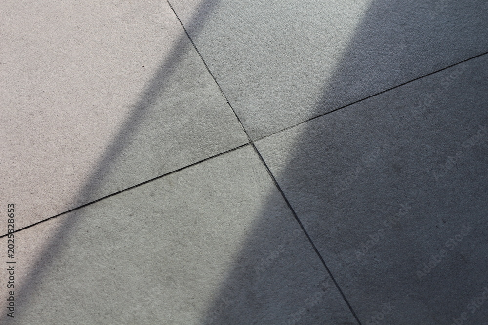 Fototapeta premium Geometric pattern of light and shadow on textured stone tiles