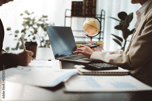 Business people collaborating on a project, analyzing financial data, using a laptop and documents during a professional meeting in a modern office setup