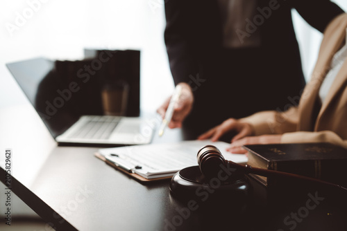 Foto Legal professionals analyzing a contract document with a pen, laptop, gavel, and