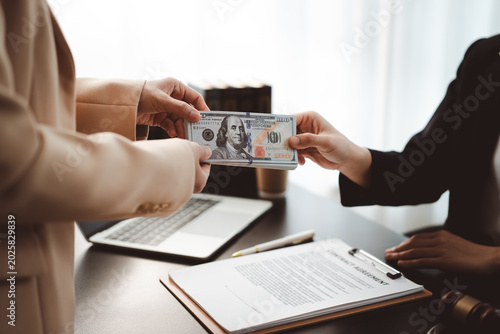 Photography Business hands exchanging a stack of $100 bills over a contract on an office des