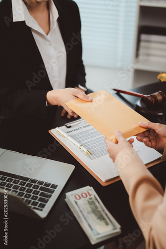 Businesswoman giving envelope with money to another person as a bribe in an illegal deal, highlighting concepts of corruption, illegal payments, and financial crime