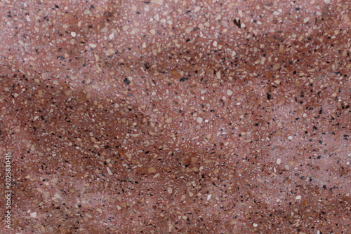 Close-up texture of a red terrazzo surface with small chips of various colors