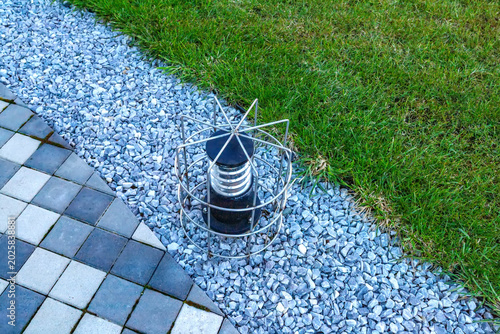 A street lamp and a winding stone path in green grass. Top view.