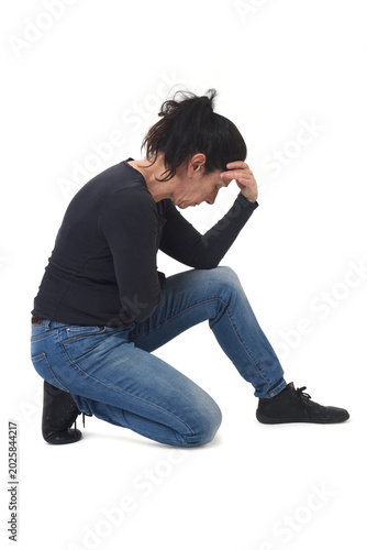 Foto side view of a woman kneeling looking down and hand on forehead