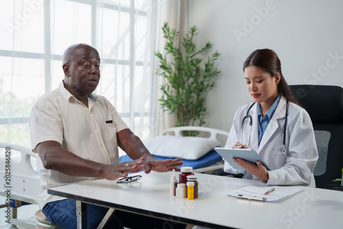 Foto Asian female doctor having a consultation with an African American senior patien