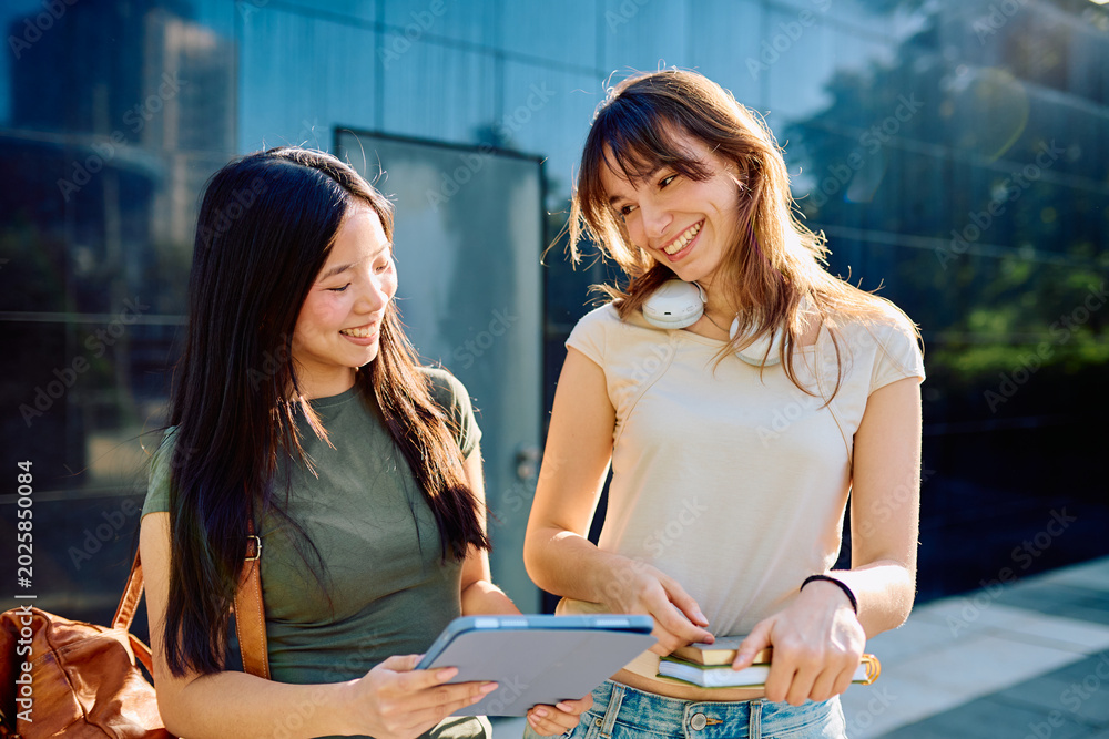Fototapeta premium Two happy students smiling and learning together outdoors on university campus