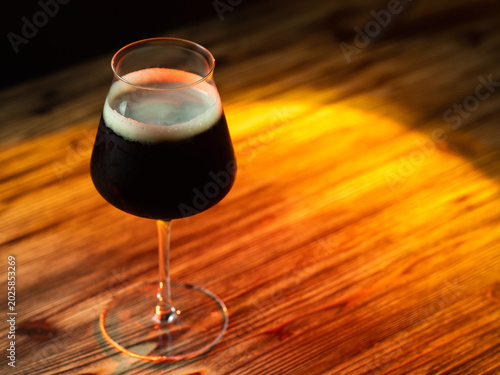 Imperial stout in a tall glass on a wooden table