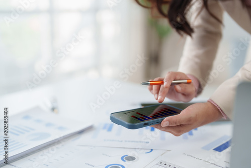 Cuadro en lienzo Person holding a smartphone, analyzing financial data with bar graphs on the scr