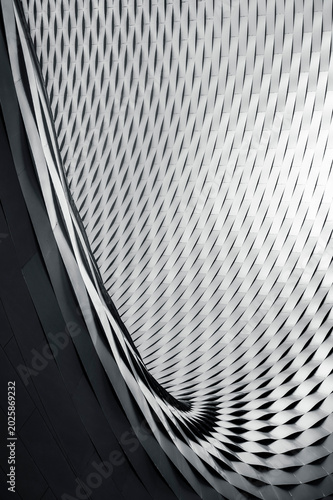 An abstraction in the form of a curved lattice with a smooth geometric rhythm in monochrome. Vertical black and white photo
