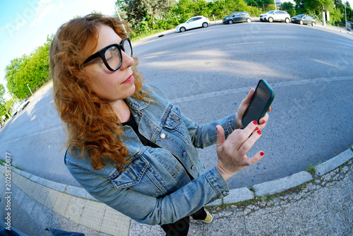 Konstfotografi Woman using smartphone outdoors on city street