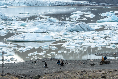 Tourists admiring the glacier lagoon with icebergs at the foot of the Vatnajokull Glacier or Vatna Glacier, the largest and most voluminous ice cap in Iceland, and the second largest in area in Europe