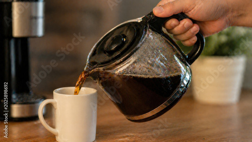 Close-up of coffee being poured from glass pot into mug, symbolizing freshness, caffeine, and daily ritual