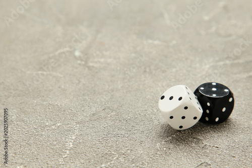 Two black and white dice on grey concrete background. Game cube