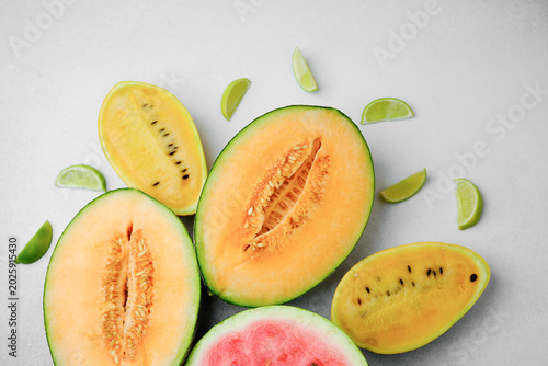 Fotografía Assortment of sliced melons and fresh lime wedges on a light surface