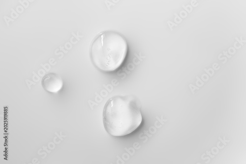 Transparent niacinamide serum drops on light background. Clear skincare texture hyaluronic acid cosmetic product, macro