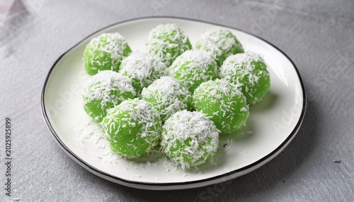 traditional indonesian klepon balls covered in shredded coconut made from glutinous rice flour with sweet palm sugar filling served on white plate