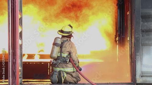 Firefighter works to control flames in dark building during late night operation in urban area