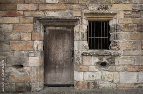 Detail of a weathered sandstone wall with a door.