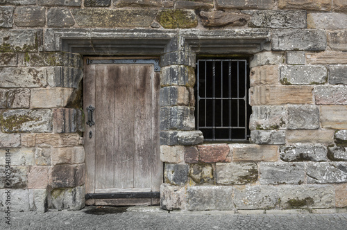 Detail of a weathered sandstone wall with a door.