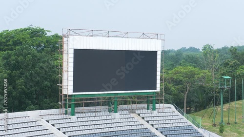 Large blank stadium LED scoreboard screen mockup surrounded by scaffolding 4K