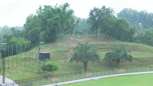 Natural green hill gallery with lush trees next to stadium outfield on overcast day 4K