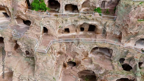 Aerial close-up shot of Vardzia cave monastery rooms and tunnels. Detailed drone view of the ancient rock-hewn windows and chambers carved into the steep cliffside in Georgia