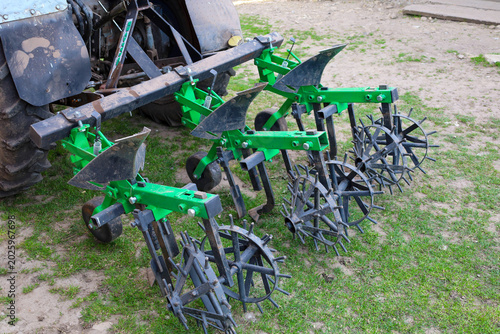 Εκτύπωση καμβά ​A green agricultural cultivator with metal spike wheels is attached to the rear part of a tractor