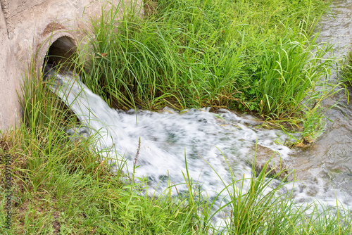 TREATED WASTEWATER FLOWING FROM AN URBAN DRAINAGE PIPE INTO A STREAM - THIS IMAGE SHOWS WATER TREATMENT, SANITATION, ECOLOGY AND ENVIRONMENTAL CONSERVATION IN A NATURAL WATERWAY