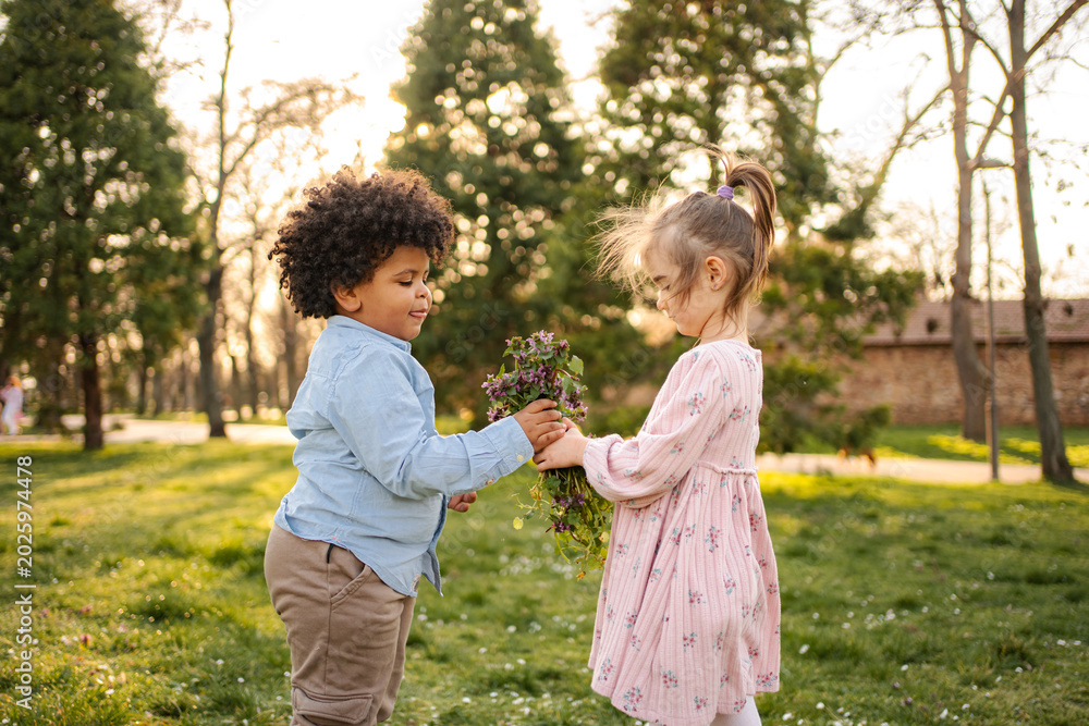 Obraz premium Children sharing flowers in park expressing friendship