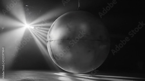 Abstract suspended sphere illuminated by spotlights, casting shadows on the dark surrounding environment