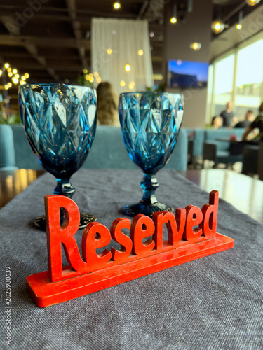 a red wooden sign reserved on a table against the background of two transparent glasses. High quality photo