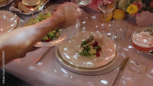 Unrecognizable waiter serving salad onto guest plate in slow motion at luxury wedding banquet. Anonymous caterer placing gourmet food at restaurant dinner. Elegant hospitality. 4K stock footage.