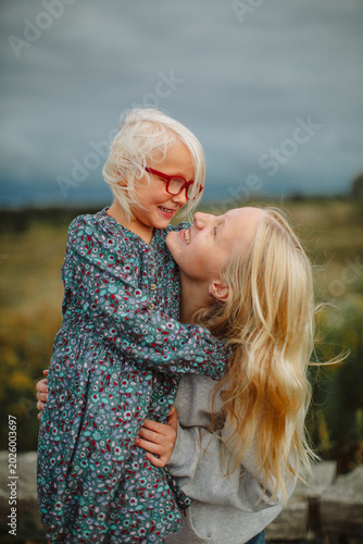 Happy sisters hugging outdoors before a storm – candid family lifestyle portrait