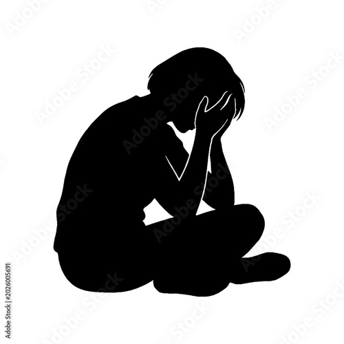Silhouette of a person sitting and feeling depressed with hands on face.