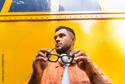 Young man holding spectacles against vibrant surface