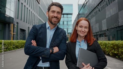 Caucasian confident business woman man looking at camera smiling posing in city successful happy businesspeople hands crossed outdoor office building colleagues coworkers partners female male together