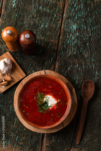 Traditional Ukrainian borscht soup with sour cream and dill in a clay bowl