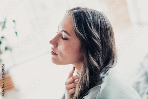Billede på lærred Young woman relaxing with eyes closed, hand at throat, pensive calm portrait in