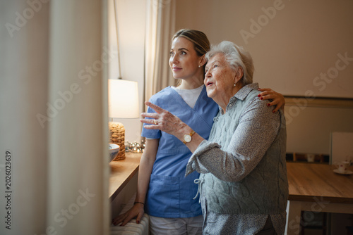 Caring healthcare worker visiting a senior patient at home, hugging her.