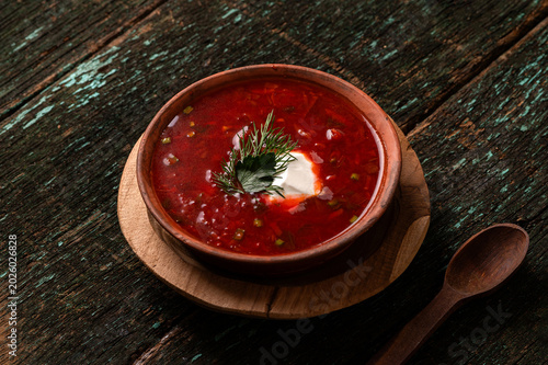Traditional Ukrainian borscht soup with sour cream and dill in a clay bowl
