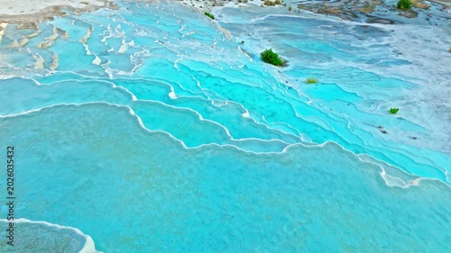 Aerial view of Travertines of Pamukkale, Turkey. Turquoise thermal pool surrounded by white limestone creates a scenic natural landmark view.
