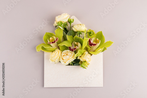 Floral envelope with roses and orchid on pastel background