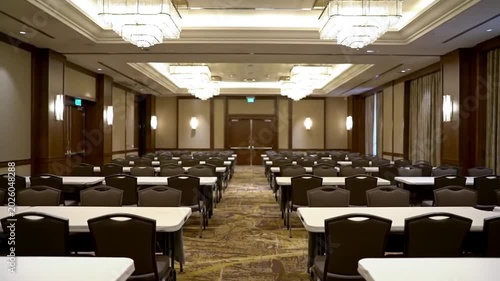 Conference room setup with rows of empty tables and chairs awaits a professional business meeting in a luxury hotel hall.