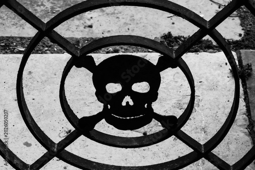 La sagoma in ferro battuto di un teschio, simbolo della morte, su una cancellata in un cimitero