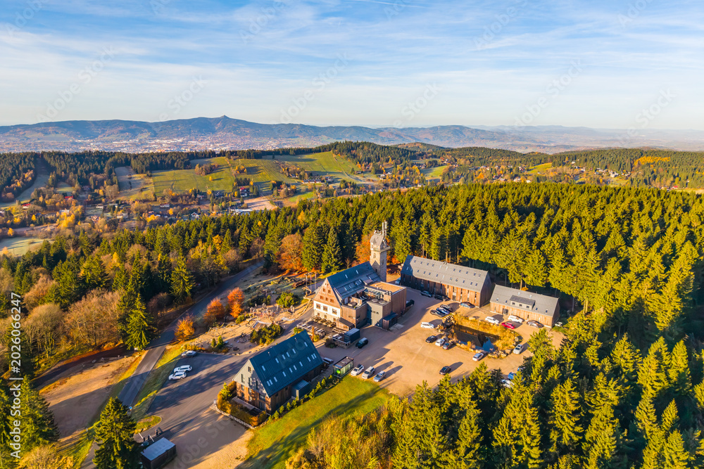 Fototapeta premium Kralovka Lookout Tower offers breathtaking views of the Jizera Mountains. Nestled in vibrant autumn colors, it invites visitors to enjoy nature's beauty and tranquility.