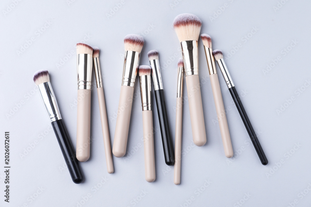 Fototapeta premium Many clean makeup brushes on light grey background, flat lay